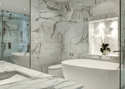 A luxury bathroom surround in marble with a deep white bathtub in the center.