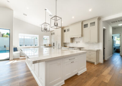 A beautiful traditional white kitchen design with hardwood floors and a wall of windows.