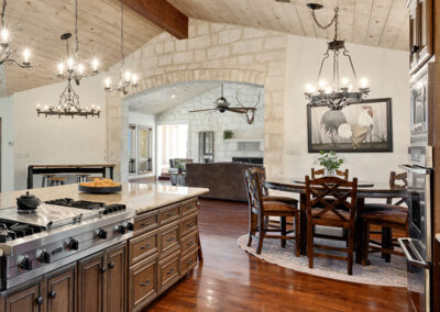 A renovated kitchen featuring hardwood floors, wooden ceiling beams and gray cabinets.